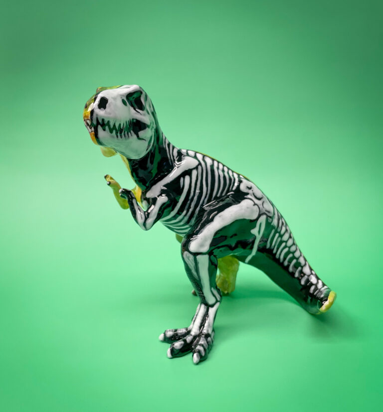 A black and white model of a dinosaur skeleton, resembling a T. rex, stands against a bright green background.